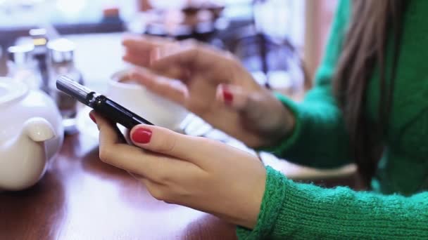 Mujer está utilizando el teléfono inteligente en un café, escribiendo un mensaje en la red social . — Vídeos de Stock