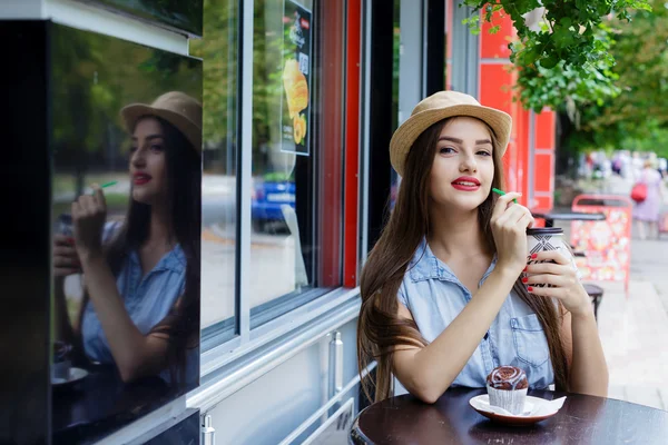 Piękna dziewczyna w picie kawy z muffin kawiarnia na świeżym powietrzu — Zdjęcie stockowe
