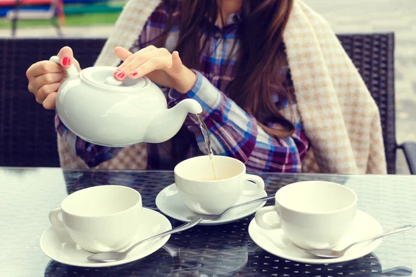 Mujeres manos vierte té de una tetera en una tazas — Foto de Stock