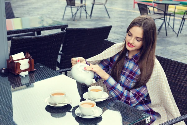 Hermosa chica vierte el té de la tetera en una tazas —  Fotos de Stock