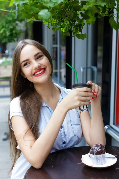 Uśmiechający się piękna dziewczyna w kawiarni na świeżym powietrzu picia kawy z muf — Zdjęcie stockowe
