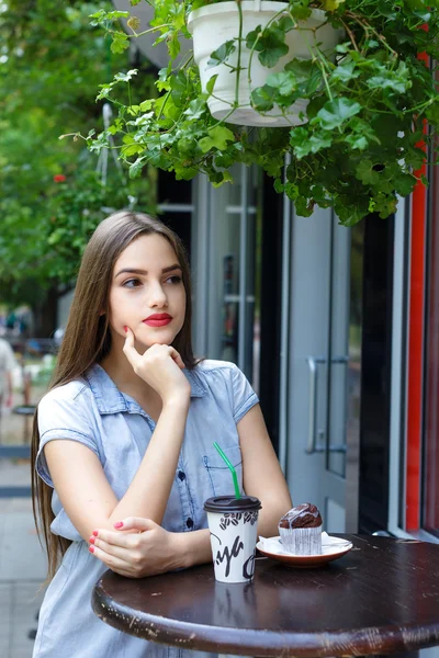Młoda atrakcyjna dziewczyna picia kawy z muffin w odkrytym caf — Zdjęcie stockowe