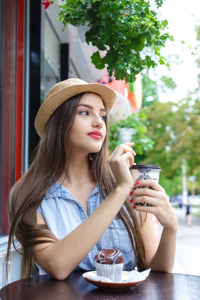 Młoda atrakcyjna kobieta picia kawy z muffin w odkrytym ca — Zdjęcie stockowe