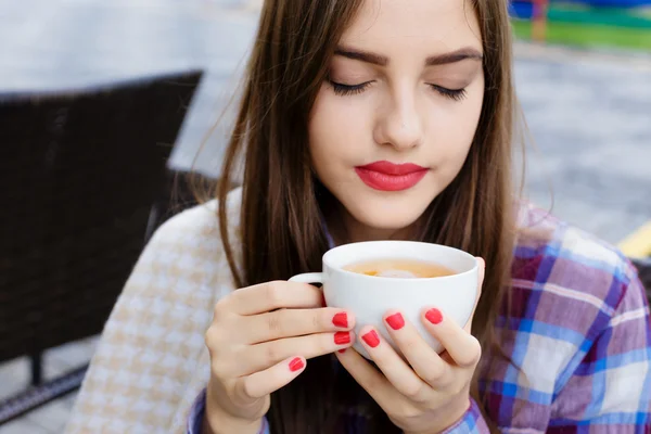 Fille enveloppée dans une couverture buvant du thé dans un café extérieur — Photo