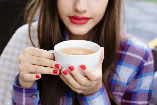 Fille enveloppée dans une couverture buvant un thé dans un café extérieur — Photo