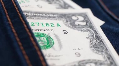 2 ve 1 Amerikan Doları banknotları dönen masanın üzerindeki kot pantolonun cebinde. Aşırı yakın plan, Yüzeyin Sığ Derinliği. İş konsepti, 21 numara...