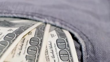 3 Amerikan bankasının 100 dolarlık banknotları dönen masanın üzerindeki kot pantolonun cebinde. Aşırı yakın plan, Yüzeyin Sığ Derinliği. İş konsepti.