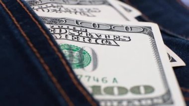 3 Amerikan bankasının 100 dolarlık banknotları dönen masanın üzerindeki kot pantolonun cebinde. Aşırı yakın plan, Yüzeyin Sığ Derinliği. İş konsepti.