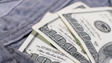 Üç Amerikan bankasının 100 dolarlık banknotları dönen masanın üzerindeki kot pantolonun cebinde. Aşırı yakın plan, Yüzeyin Sığ Derinliği. İş konsepti.