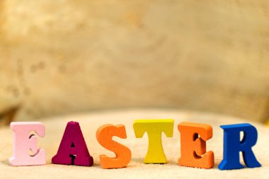 Tahta masa arkasında renkli oyuncak alfabesinin harfleri yazılı Paskalya tabiri. Kopya alanı olan parlak tebrik kartı tasarımı için ideal. Sığ alan derinliği.