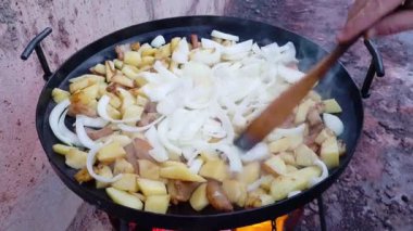 Patates ve soğan, ekicilerin diskinden yapılmış kocaman siyah bir tavada yağda kızartılıyor. Açık havada ızgara sebzeli piknik..