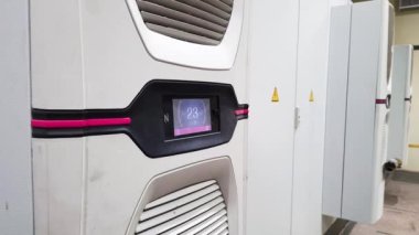 Fabrikadaki otomatik kontrol odasındaki elektrikli ekipman dolabının kapısındaki beyaz, büyük endüstriyel klima..