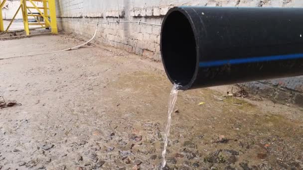 Water flow from black plastic drain pipe on an industrial building after rain — Stock Video