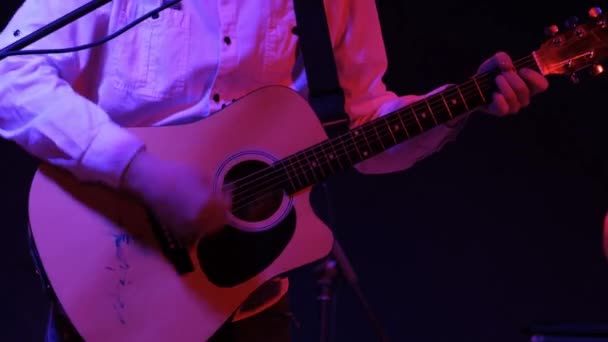 남자 리듬 기타 연주자 가 클럽에서 록 콘서트에서 어쿠스틱 기타를 연주하는 모습. 붉은 조명, 손을 감는 모습. — 비디오