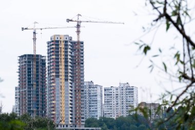 Yeni elit bir komplekste, modern yerleşim bölgesi yüksek apartmanlarının ya da gökdelenlerin inşa edildiği bir şantiyede iki vinç..