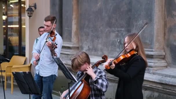 三个年轻的街头音乐家在大街上用大提琴和小提琴演奏音乐 Ukraine Lviv September 2021 — 图库视频影像