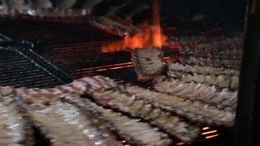 Pek çok domuz pirzolası bir restoranda dönen bir tel askıda ızgara yapıyor. Video arkaplanı.