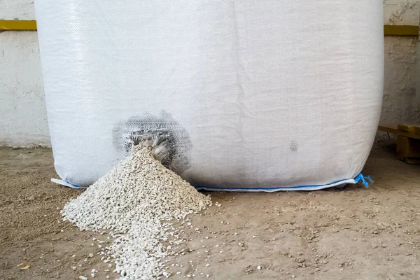 粒状矿物肥料从仓库内的一个大袋子上的孔中漏出 储存硫酸铵的有缺陷 漏水袋 图库图片