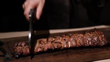 Kasap pirzolası. Karanlık bir odada tahta tepside baltayla ızgara. Yavaş çekim