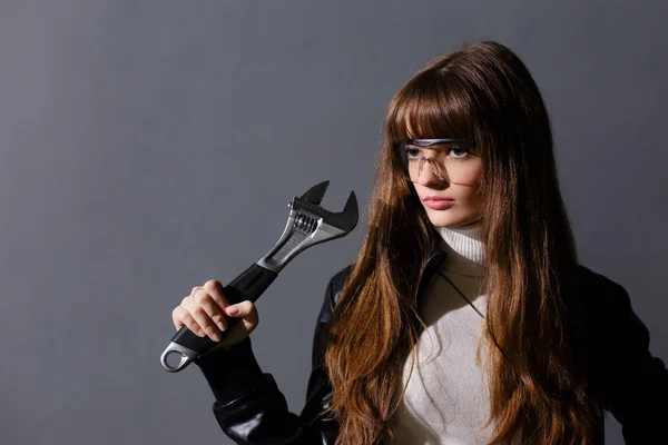 Chica en gafas protectoras con llave ajustable en una espalda oscura —  Fotos de Stock