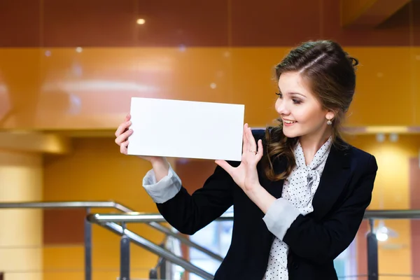 Mujer hermosa joven mirando una tarjeta blanca en blanco — Foto de Stock