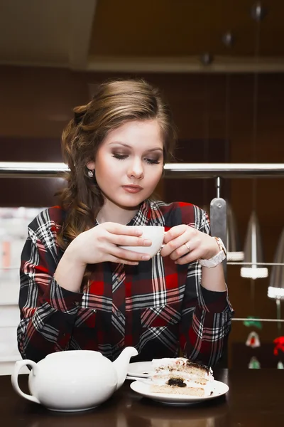 Jovens mulheres em uma camisa xadrez bebendo chá em um café — Fotografia de Stock