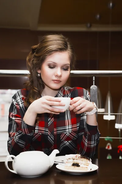 Mujeres jóvenes en una camisa a cuadros bebiendo té en un café — Foto de Stock