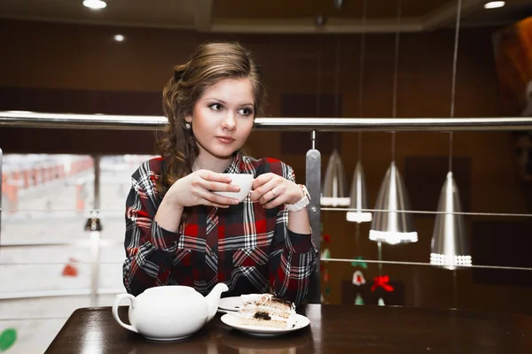 Mujeres jóvenes en una camisa a cuadros bebiendo té en un café — Foto de Stock