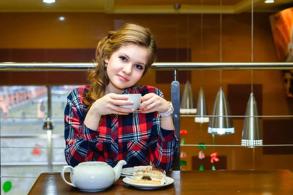 カフェでお茶を飲んだり、格子縞のシャツの若い女性 — ストック写真