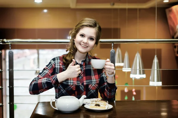 Sonriendo hermosas mujeres en una camisa a cuadros bebiendo té en un café — Foto de Stock