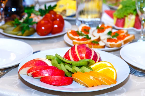 Sliced apples, oranges, marinated tomatoes, cucumbers and sandwi — Stock Photo, Image