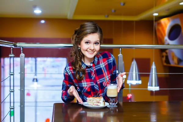 Chica sonriente agradable sentado en un café con una taza de mokachino y — Foto de Stock