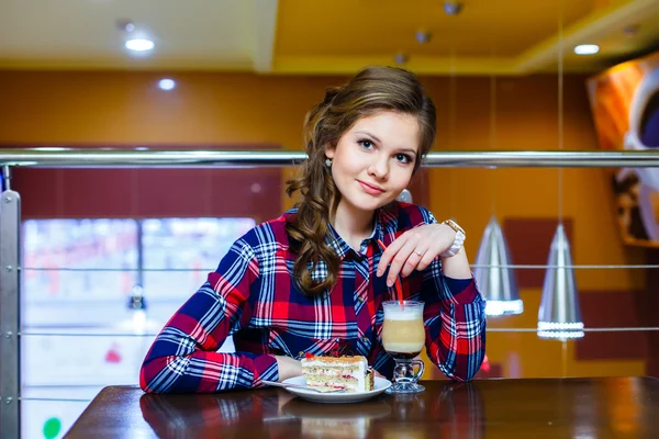 Joven hermosa chica sentada en un café con una taza de mokachino a — Foto de Stock