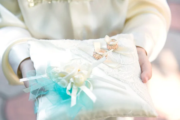 Dois belos anéis de casamento em uma almofada nas mãos de uma criança — Fotografia de Stock