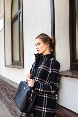 Şık bir çanta ile genç güzel kadın duruyor 