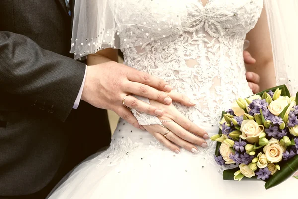 Handen van de bruidegom en de bruid close-up en bruids boeket — Stockfoto