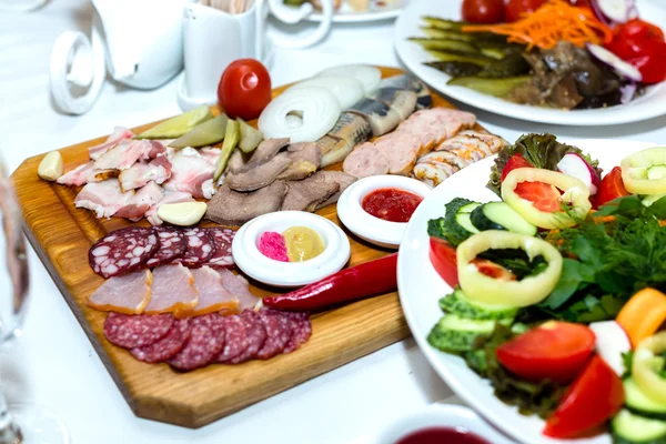 Cold meats on wooden plate on banquet table — Stok fotoğraf