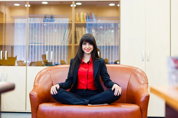 Belle fille souriante assise sur un canapé en position lotus — Photo