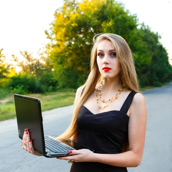 Jovem bela mulher sorridente com um laptop na estrada — Fotografia de Stock