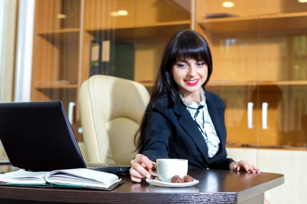 Hermosa joven toma una taza de café en una mesa en el de — Foto de Stock