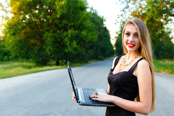 Junge schöne lächelnde Mädchen mit einem Laptop auf der Straße — Stockfoto