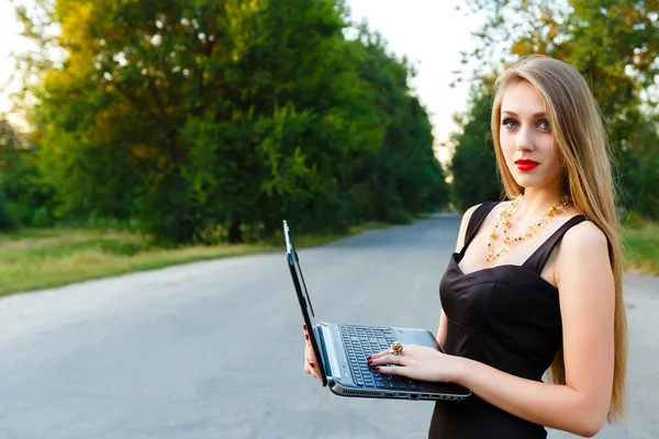 Joven hermosa mujer de negocios sosteniendo un ordenador portátil en el camino —  Fotos de Stock