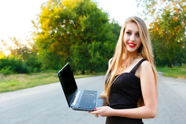 Genç güzel gülümseyen kadın yolda bir dizüstü bilgisayar ile — Stok fotoğraf