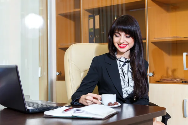 Hermosa mujer alegre en la oficina bebiendo café — Foto de Stock