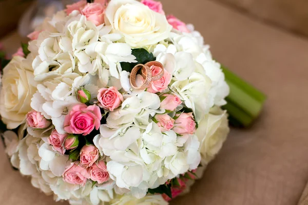 Dois anéis de casamento em um buquê de rosas vermelhas e brancas — Fotografia de Stock