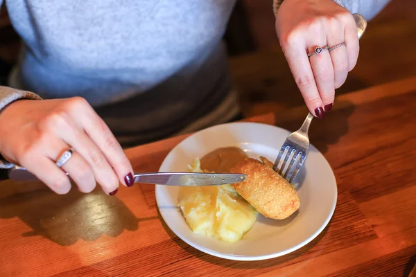 Woman uses a knife and fork for eating a cutlet — Stock Photo, Image