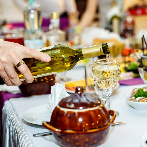 Human hand pours a white wine to wineglass — Stock Photo, Image