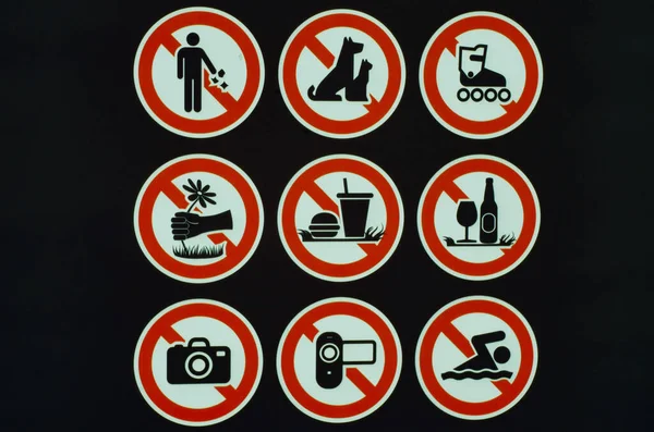 Many prohibition signs on one poster in a summer park. Do not litter, do not smoke, do not drink alcohol, do not light fires.