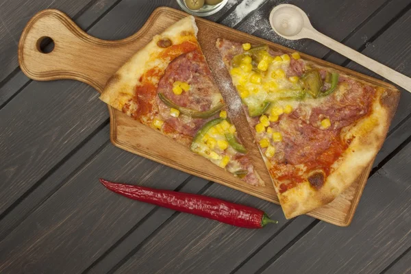 Frische Pizza auf einem Holzschneidebrett. Mahlzeiten für die Familie zubereiten. — Stockfoto