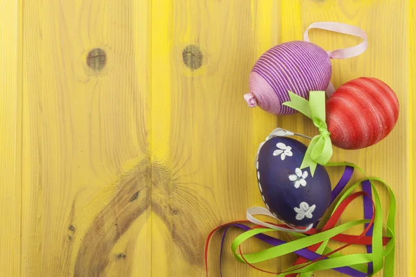 Colorate uova di Pasqua su un vecchio sfondo di legno giallo. Festeggiamo le feste pasquali. Posto per il testo. Simbolo di Pasqua . — Foto Stock